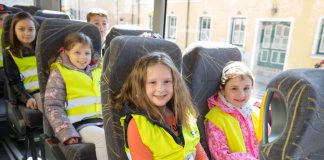 Kinder mit Warnweste im Schulbus