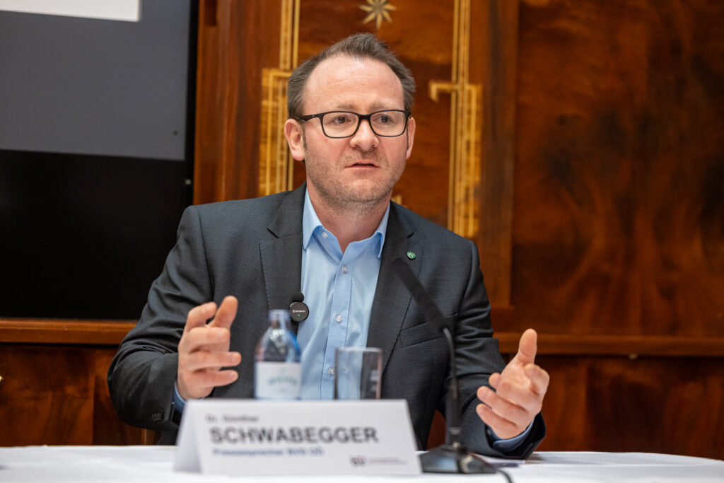 Dr. Günther Schwabegger (BVS OÖ) spricht bei der Pressekonferenz. Er gestikuliert mit den Händen. Eine Flasche Wasser steht neben dem Mikrofon vor ihm.