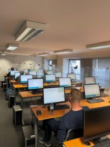 Ein Raum mit vielen PC-Sitzplätzen mit aufgedrehten Monitoren für die Führerscheinausbildung.