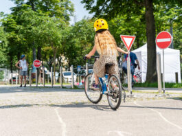 Ein Mädchen von hinten auf einem Fahrrad fährt einen Radparcours.