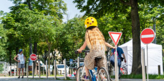 Ein Mädchen von hinten auf einem Fahrrad fährt einen Radparcours.