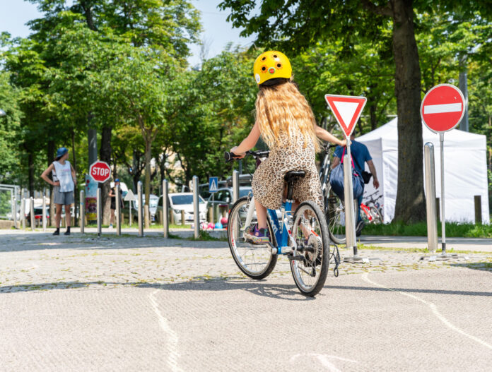 Ein Mädchen von hinten auf einem Fahrrad fährt einen Radparcours.