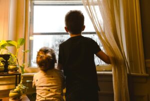 Zwei Kinder schauen aus dem Fenster