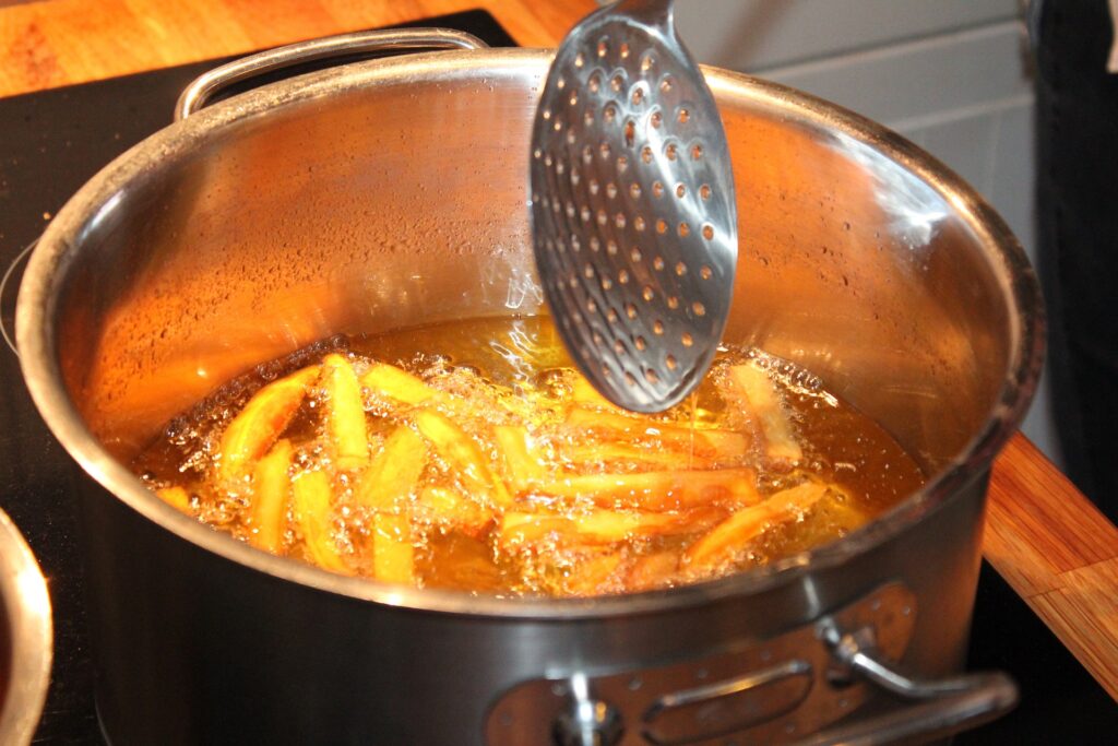 Pommes frites in einem Topf mit heißem Öl.